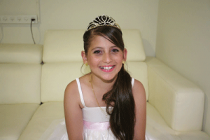 A smiling Shefa Shukrun in her bat mitzva dress. courtesy of Yael Halfon.