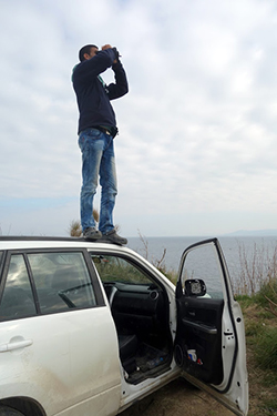 Malek Abu Grara peers out at the tiny speck on the horizon to try to determine where along the rocky coast the next refugee boat will land.